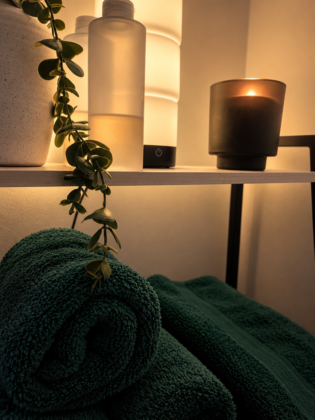 Oil, a lit candle and rolled linen towels laid out ahead of a session.