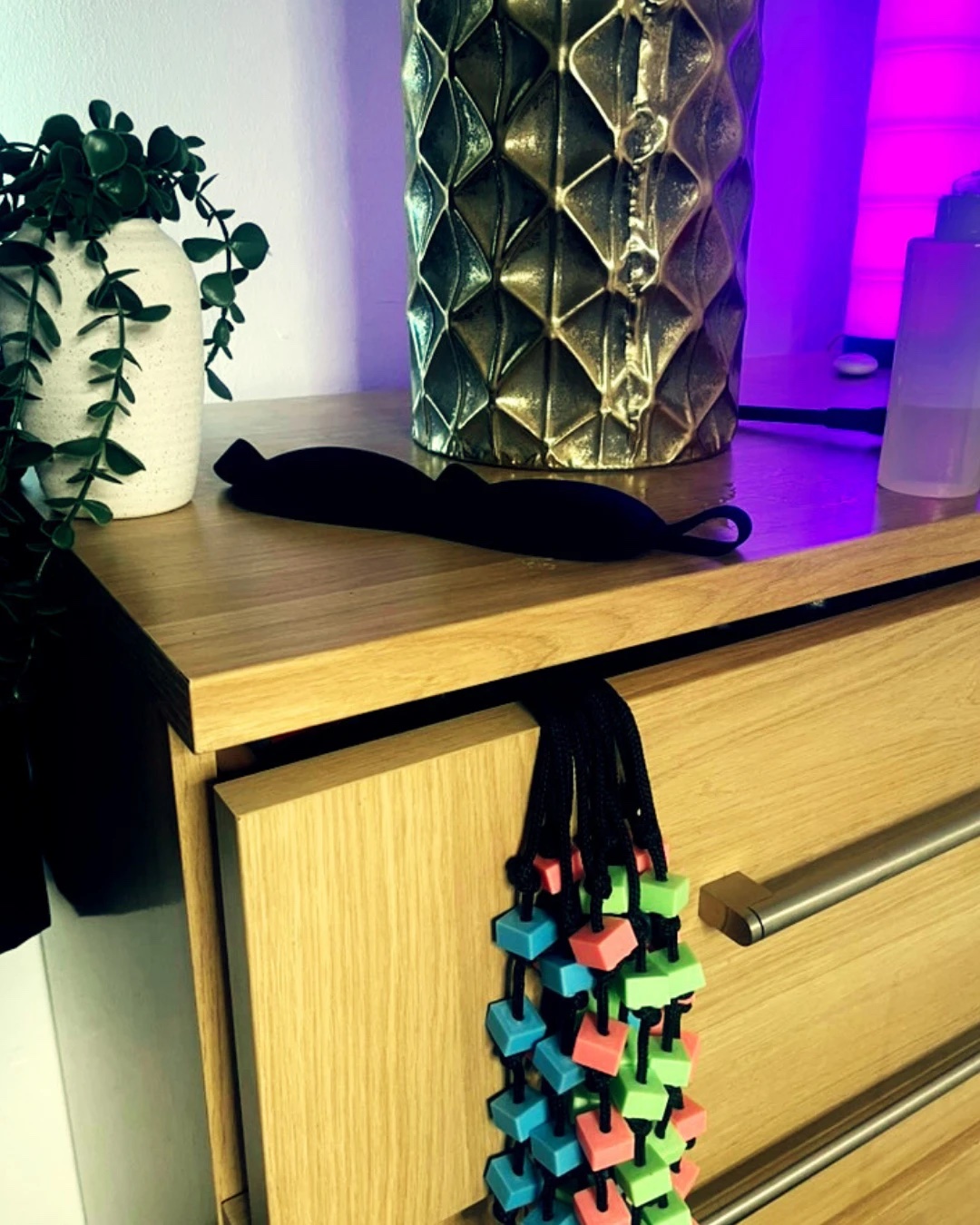 A blindfold and sensory accessories laid out on the dresser, part of the room set up for a session.